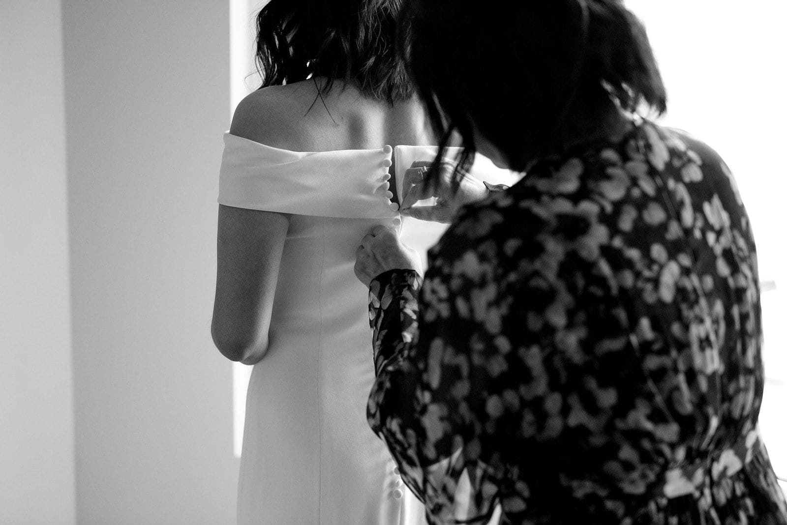 bride getting ready slips into wedding dress with mother mom emotional candid downtown toronto wedding photographer gardiner museum minimalist chic Jacqueline James Photography