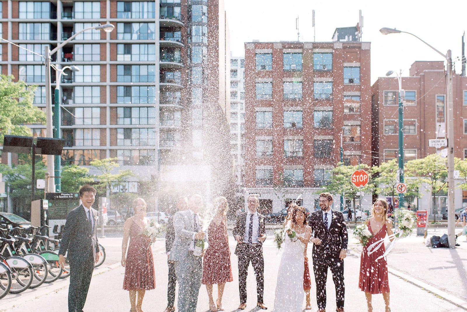 Champagne Spray Celebration in the streets Happy Joyful Spontaneous Fun with Bride and Groom and Wedding Party Downtown Toronto Wedding Photographer Jacqueline James Photography