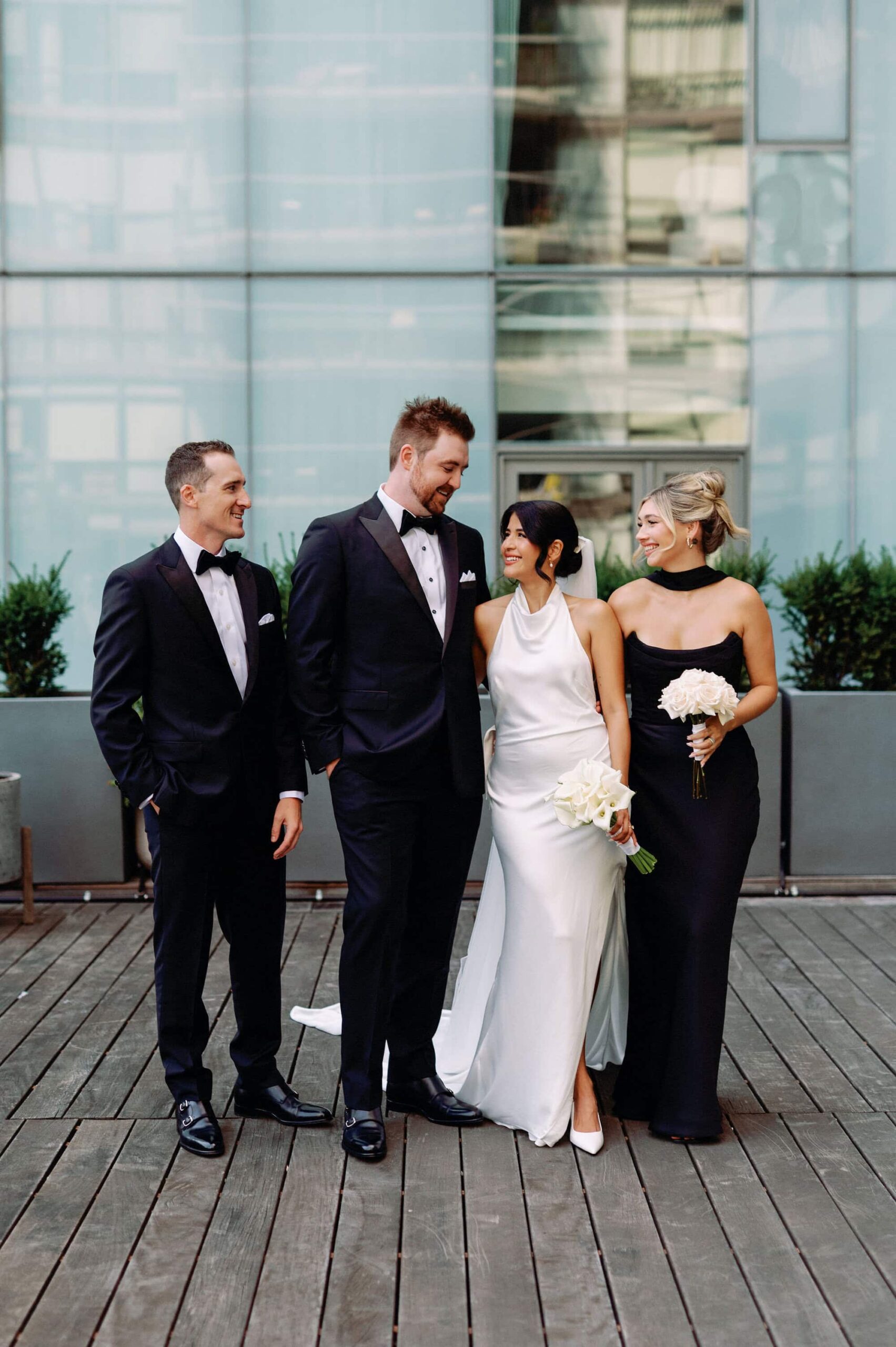Wedding party in black and white outfits posing with bride and groom at 1 Hotel Toronto
