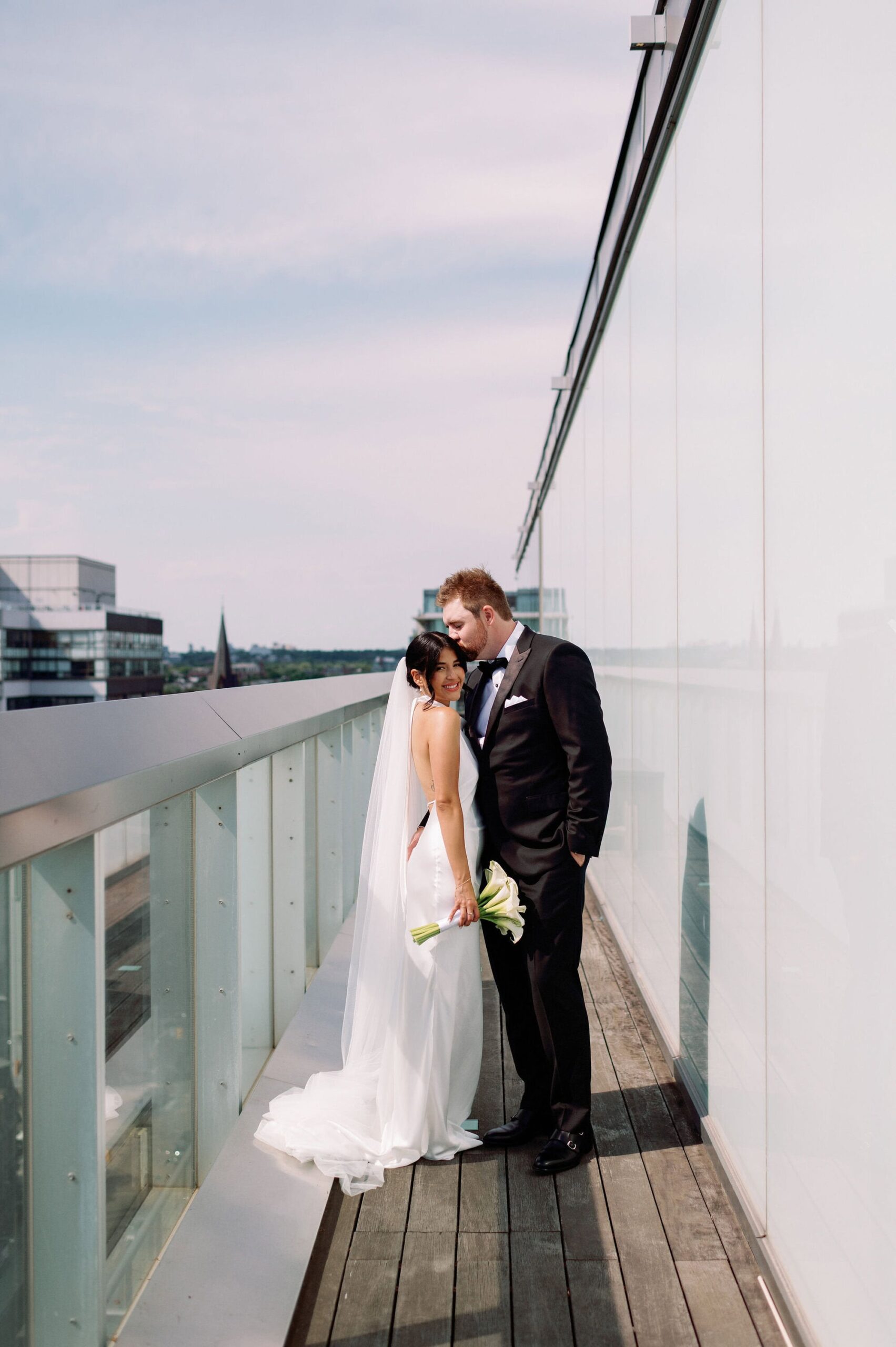 Bride and groom on rooftop balcony with CN Tower skyline view at 1 Hotel Toronto