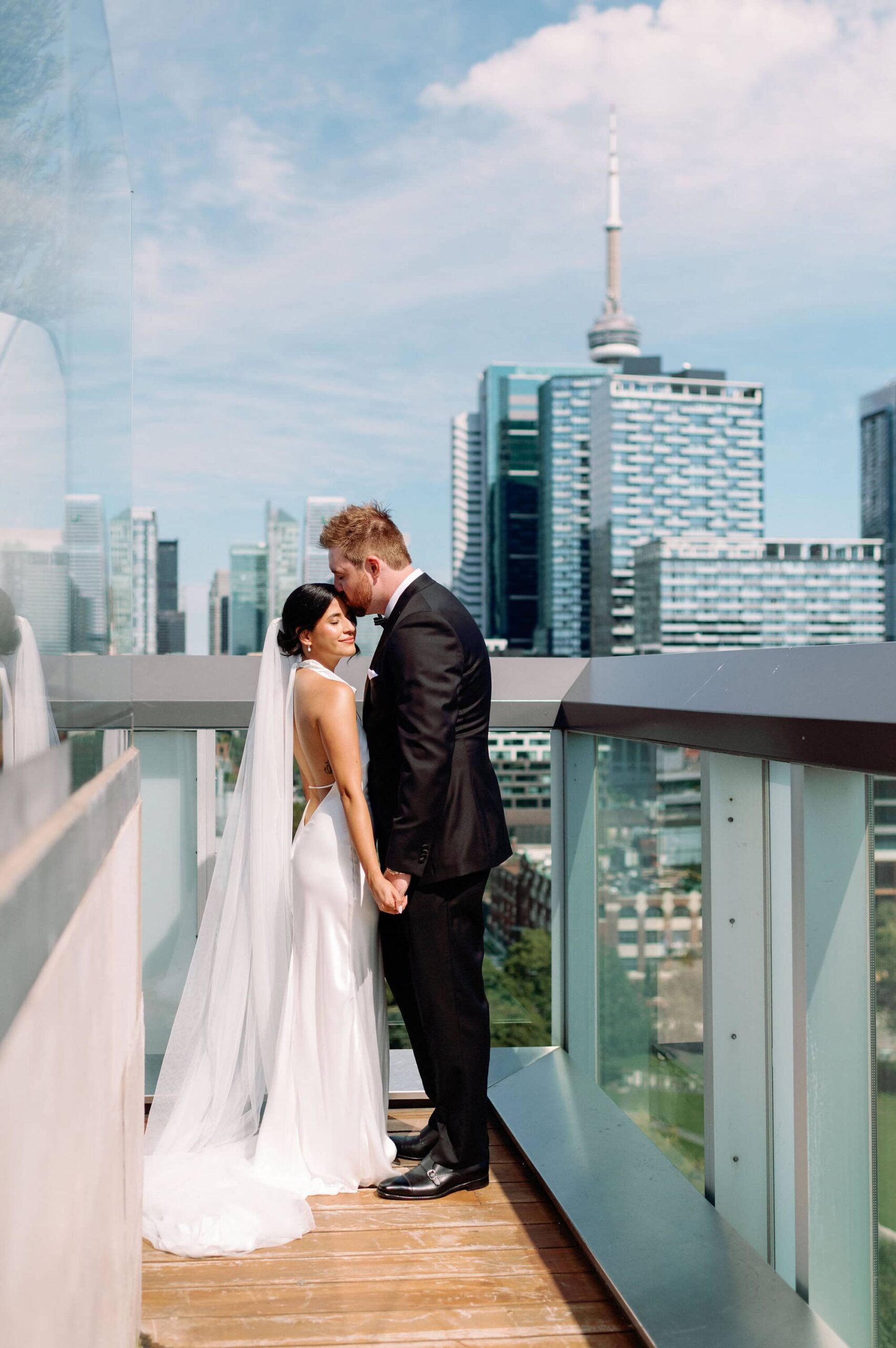 Bride and groom on rooftop balcony with CN Tower skyline view at 1 Hotel Toronto