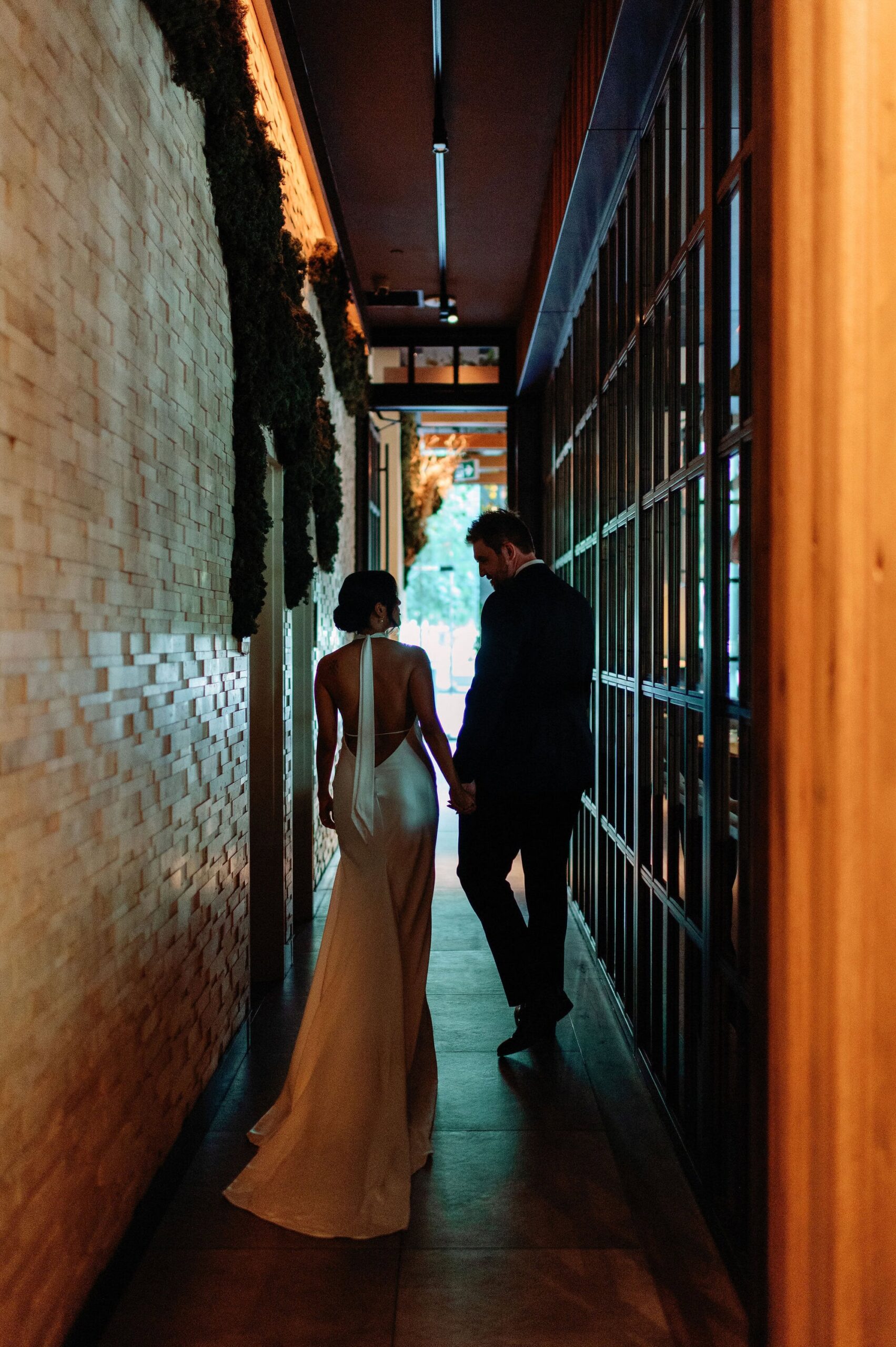 Bride and groom walking hand in hand through candlelit hallway at 1 Hotel Toronto