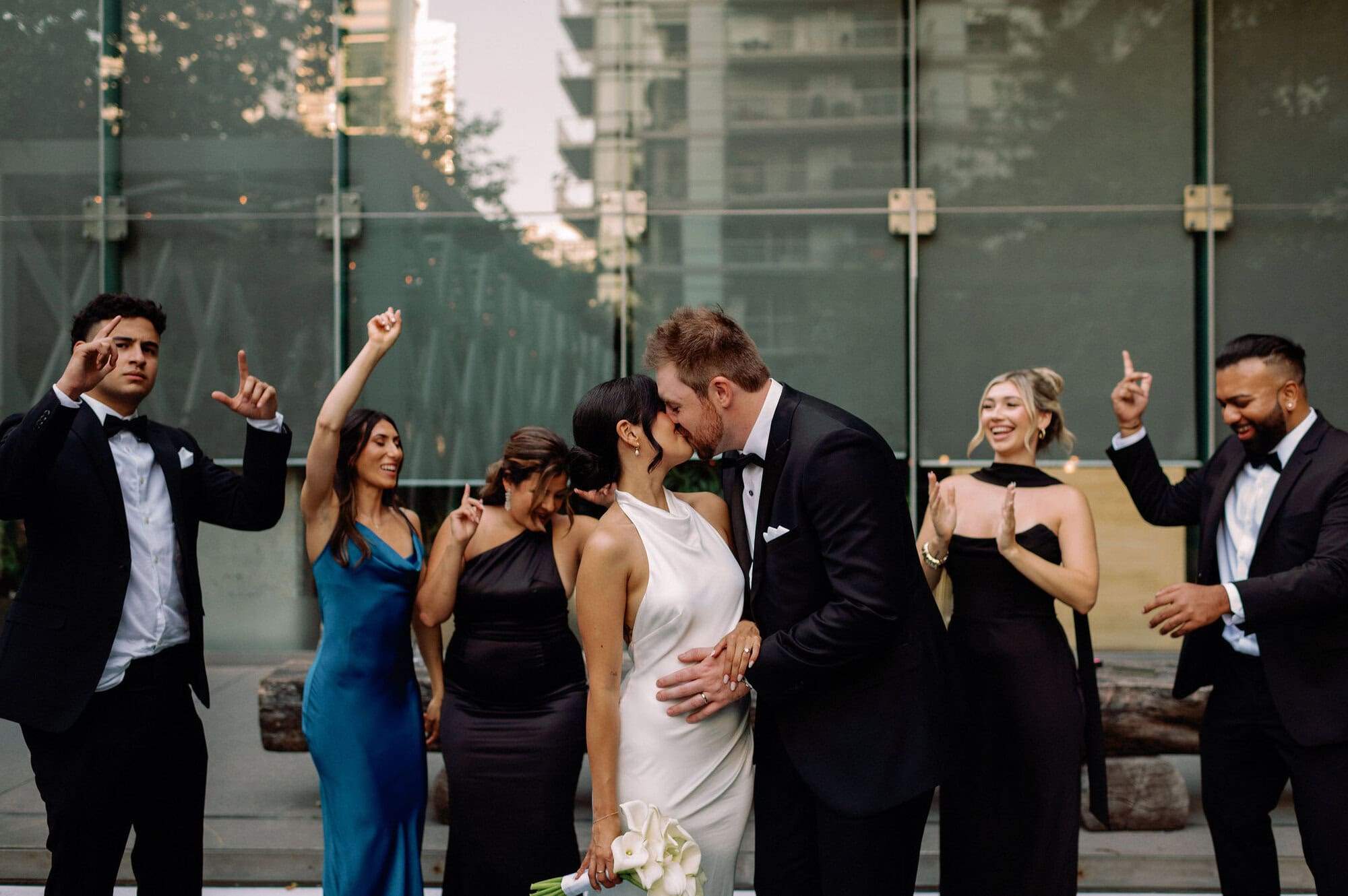 Bride and groom kiss while bridal party cheers at 1 Hotel Toronto