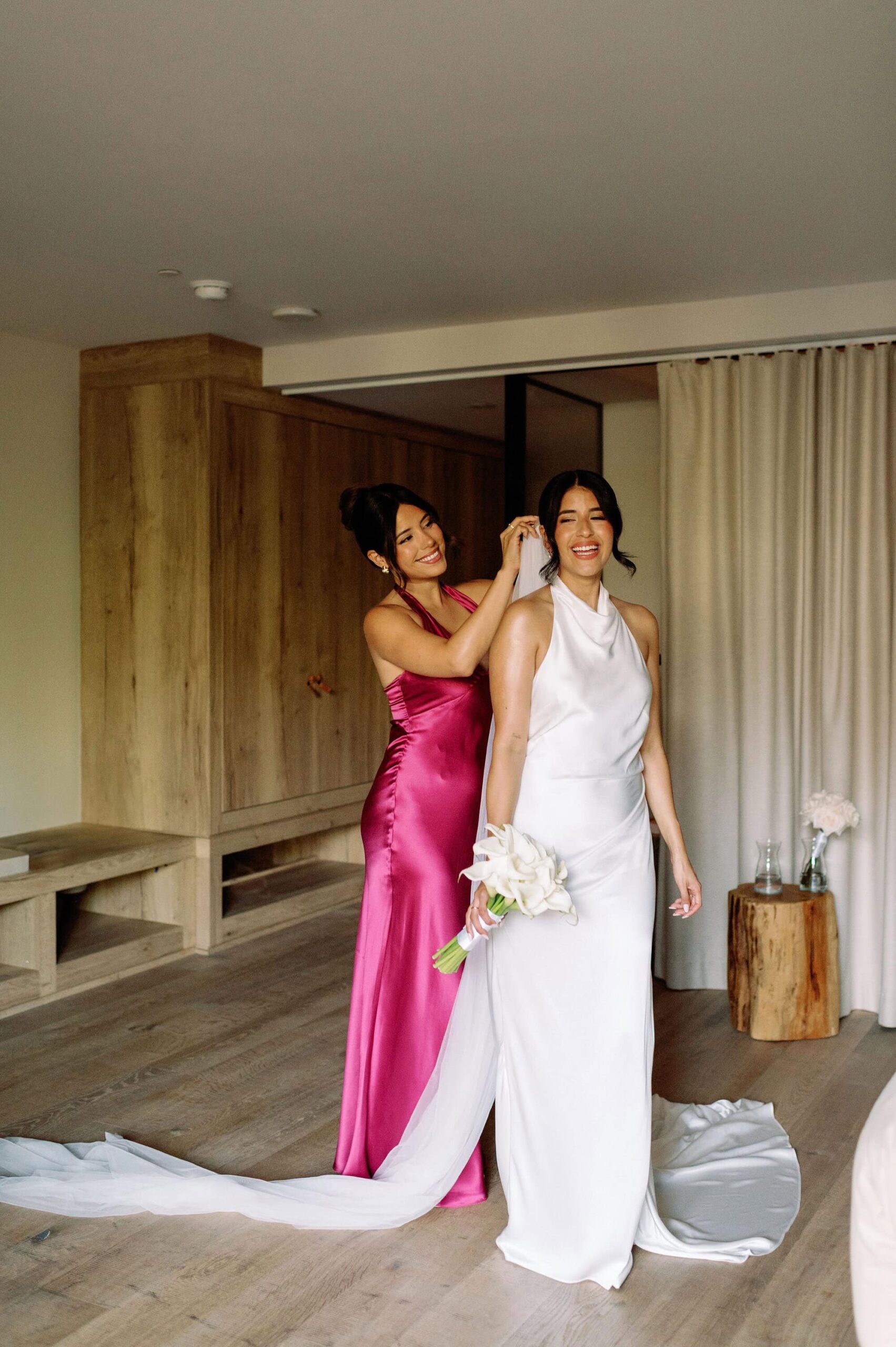 Bridesmaid helping bride with wedding dress veil at 1 Hotel Toronto suite