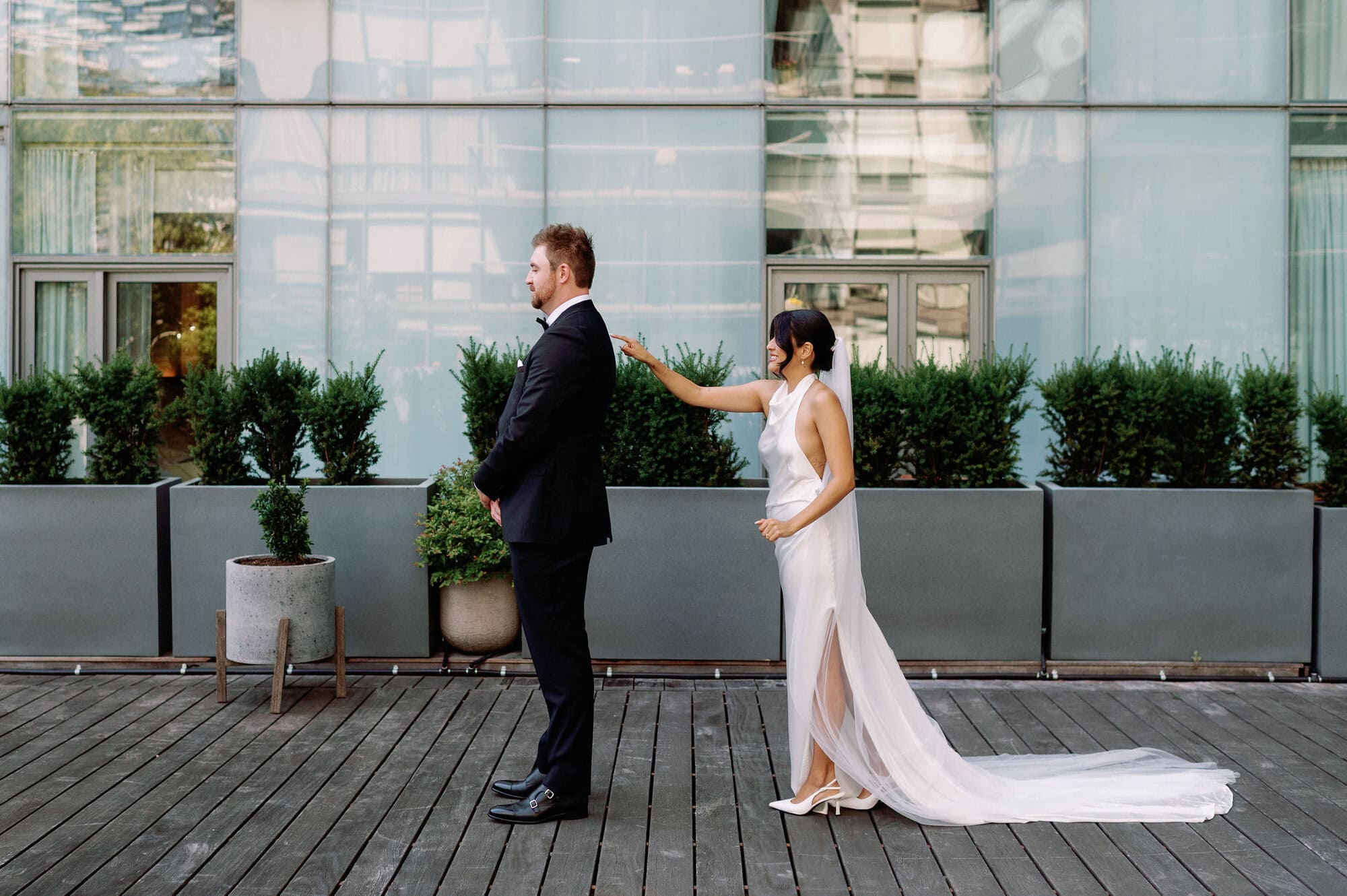 Bride tapping groom on the shoulder during first look at 1 Hotel Toronto terrace