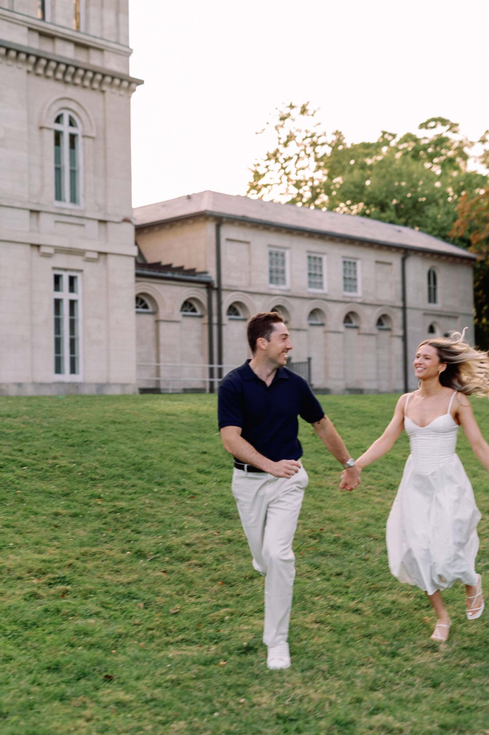 Running together across the grass in evening light at Dundurn Castle Hamilton