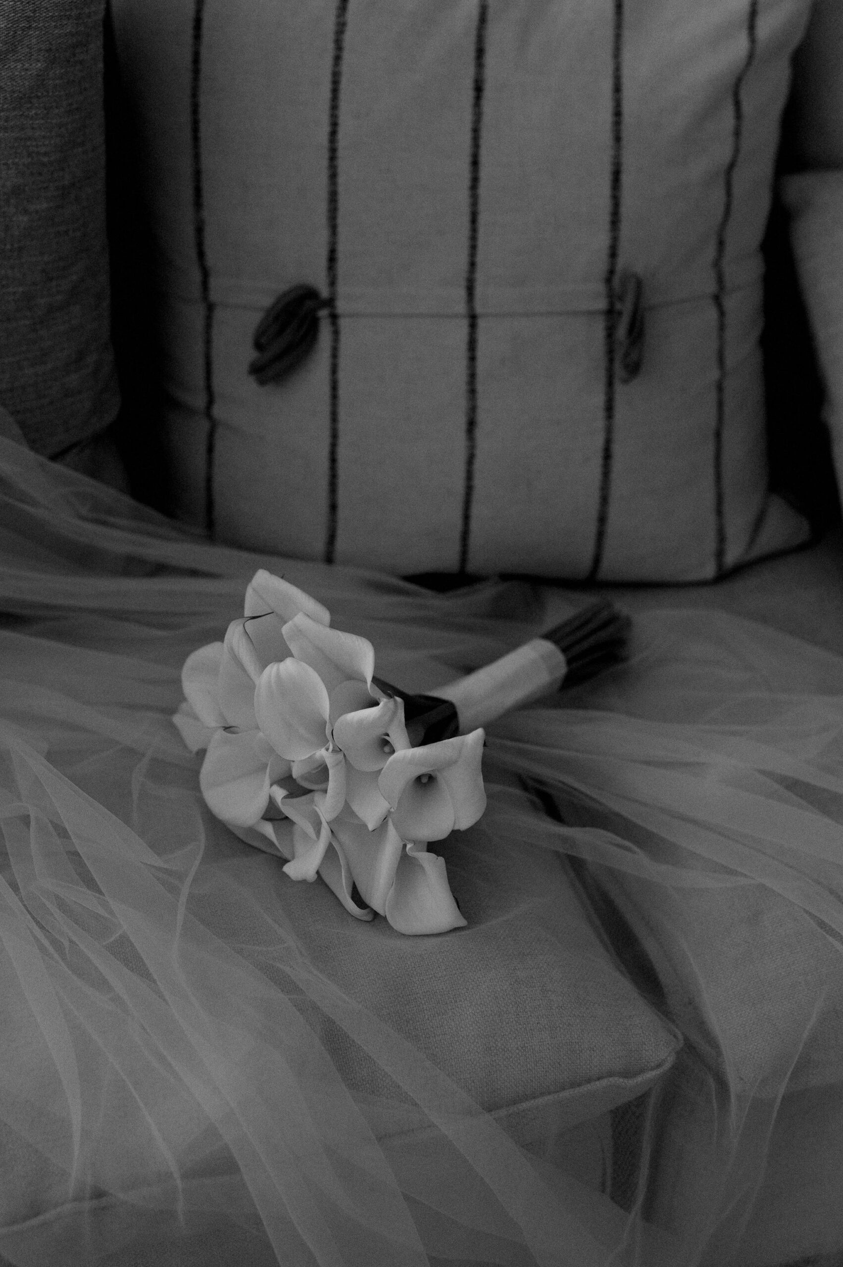 Black and white photo of the bride’s bouquet laid on the bed at 1 Hotel Toronto.