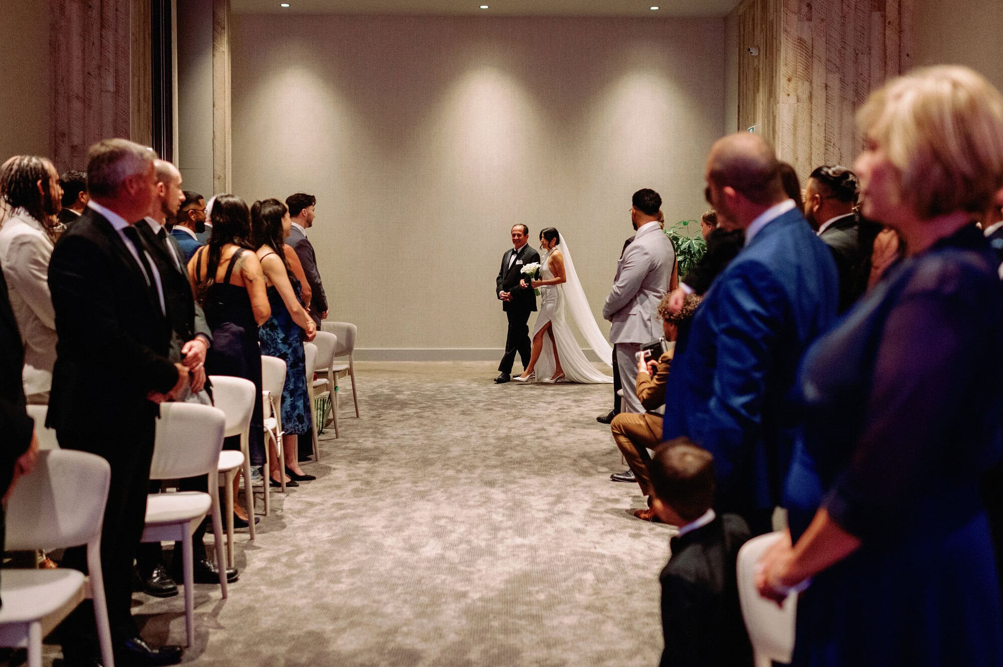 Bride and her father walking down the ceremony aisle at 1 Hotel Toronto while guests watch.