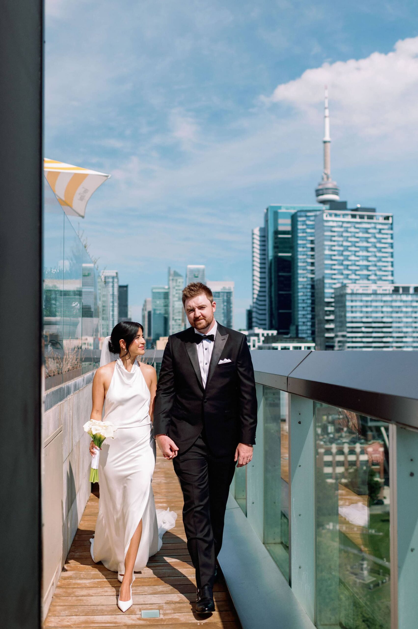 Bride and groom walking on the terrace at 1 Hotel Toronto with the downtown skyline behind them.