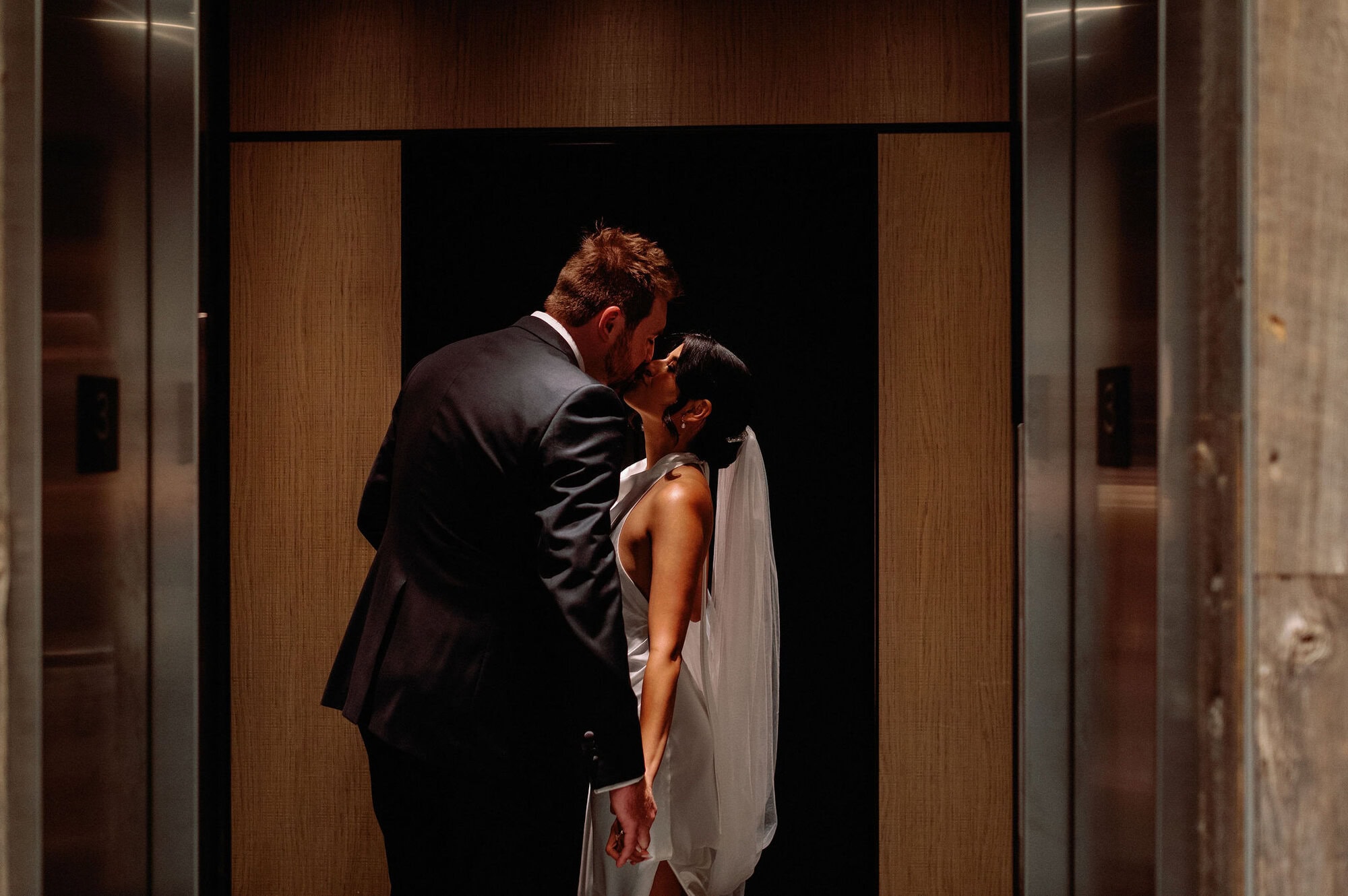 Bride and groom sharing a quiet kiss inside the elevator at 1 Hotel Toronto.