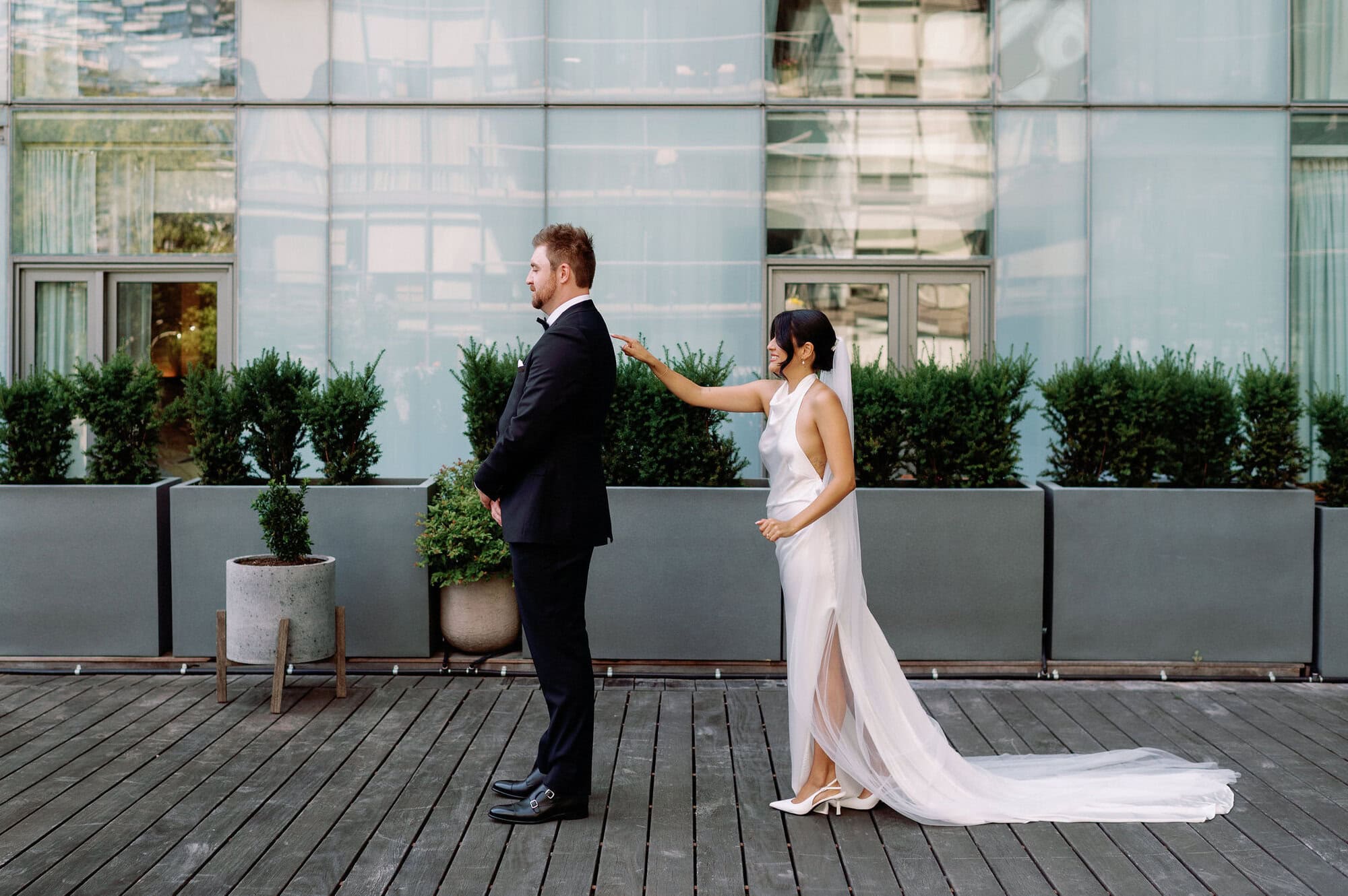 Bride reaching toward the groom during their first look outside 1 Hotel Toronto.