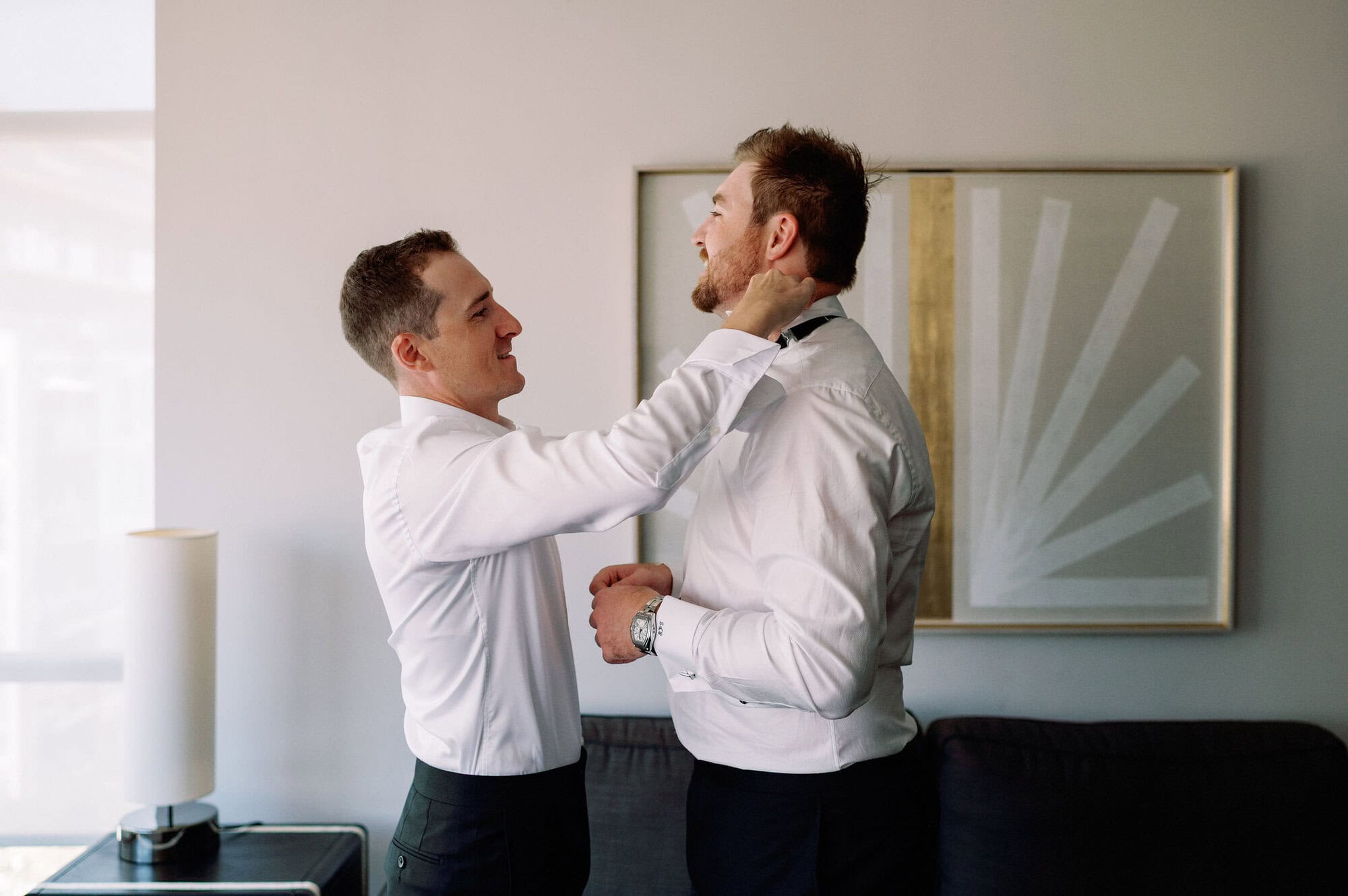 Groomsman helping the groom with his tie during getting ready moments at 1 Hotel Toronto.