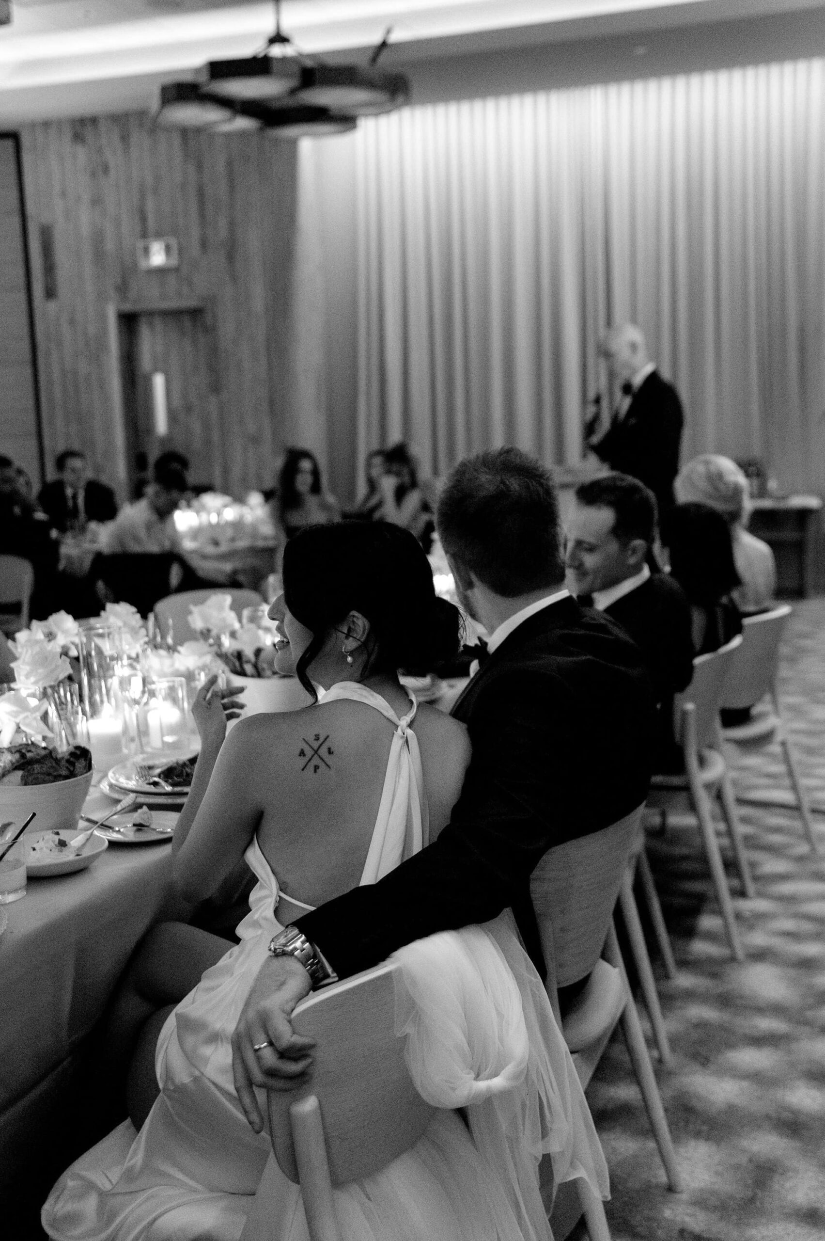 Black and white candid of the bride and groom listening to speeches at their 1 Hotel Toronto wedding