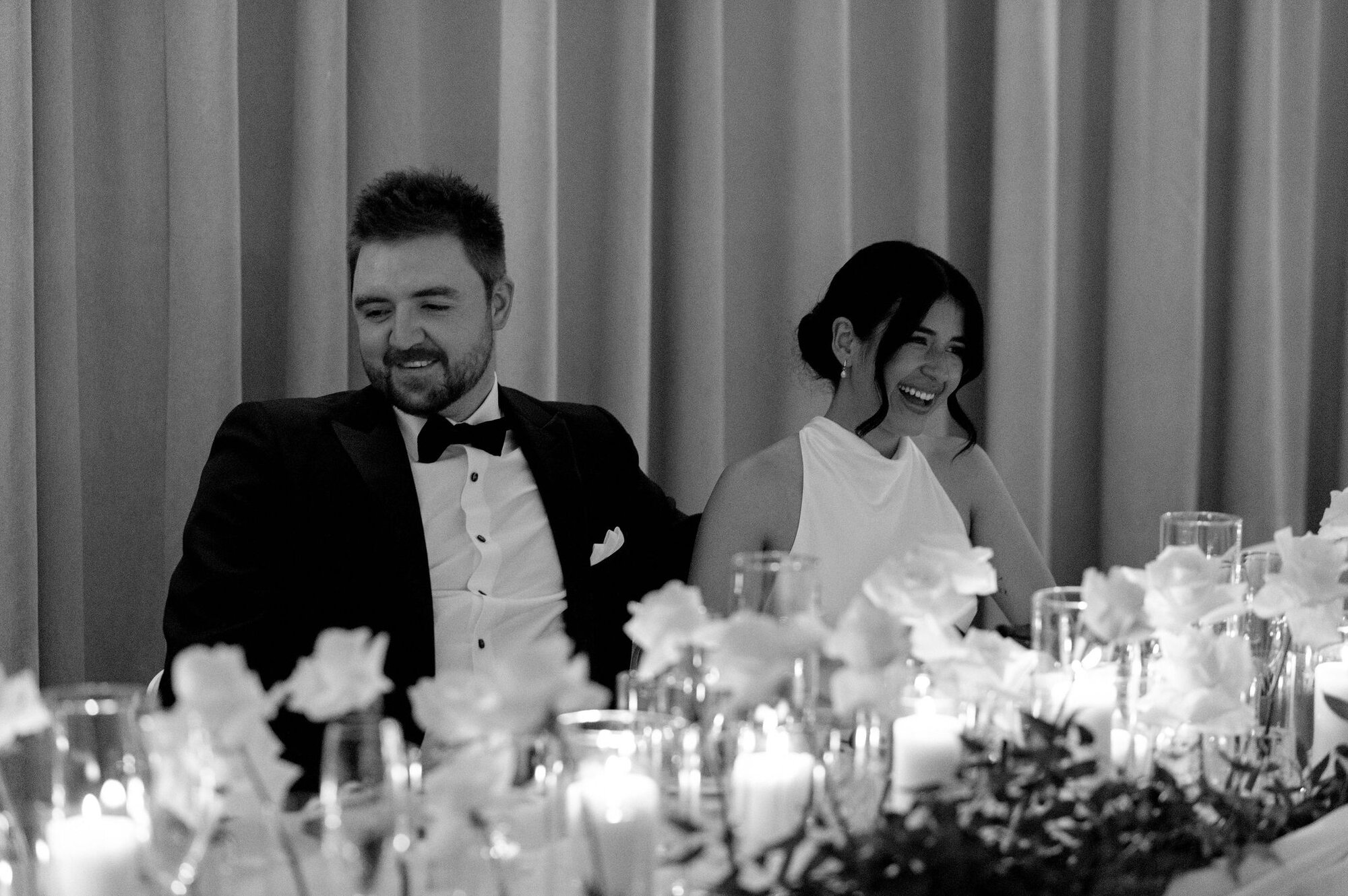 Black and white candid of the bride and groom listening to speeches at their 1 Hotel Toronto wedding.