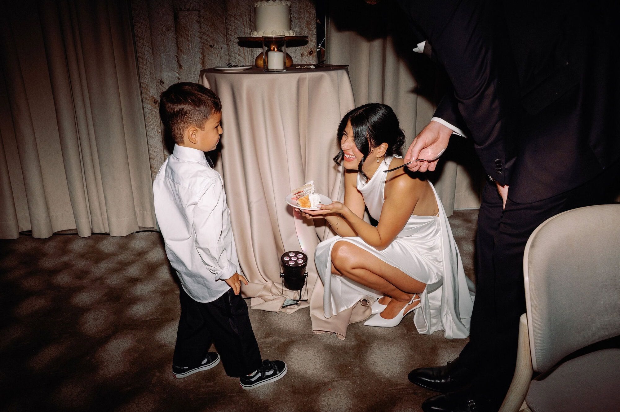 Bride crouching down to talk to the ring bearer during the wedding reception at 1 Hotel Toronto.