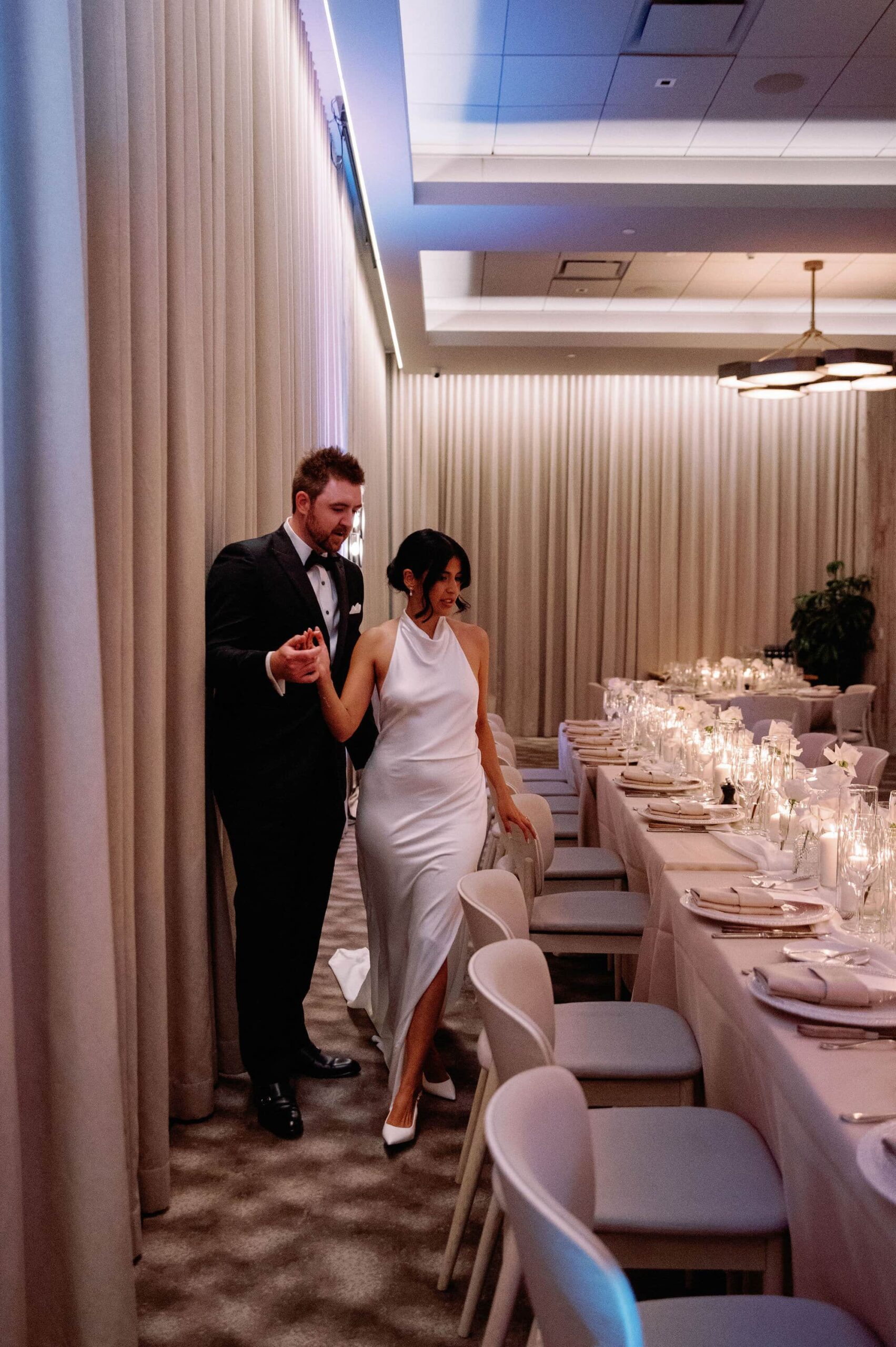 Bride and groom walking hand in hand through their candlelit reception at 1 Hotel Toronto.