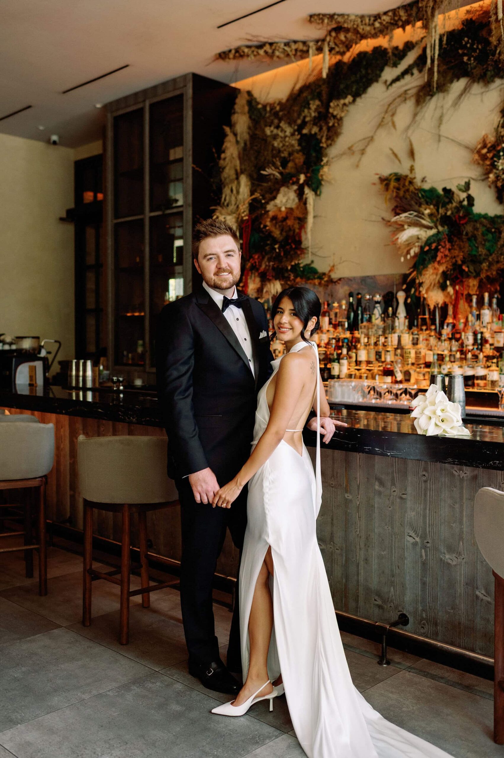 Full length wedding portrait of the couple standing in front of the bar at 1 Hotel Toronto.