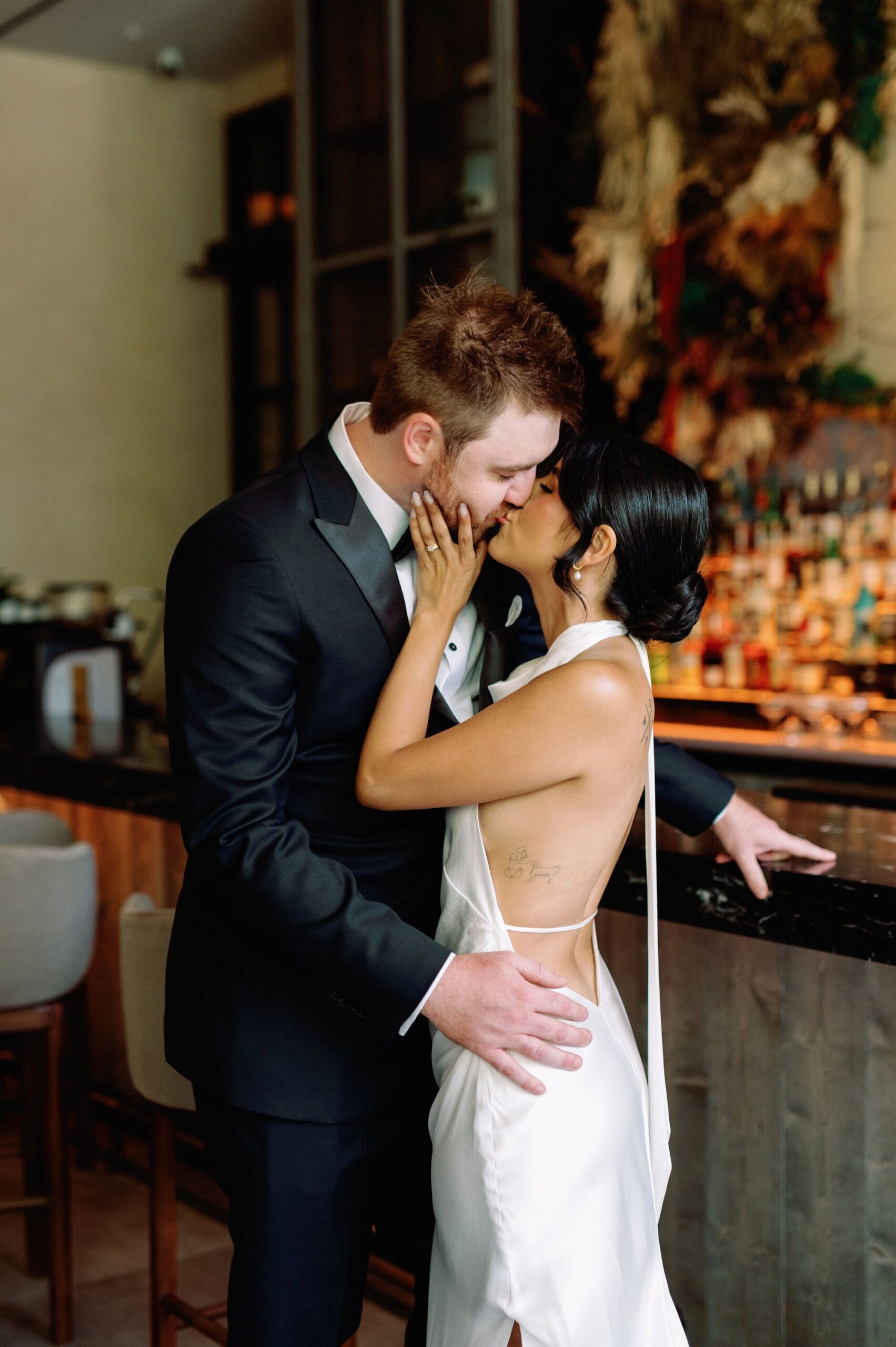 Bride and groom sharing a kiss at the bar inside 1 Hotel Toronto during their wedding portraits.