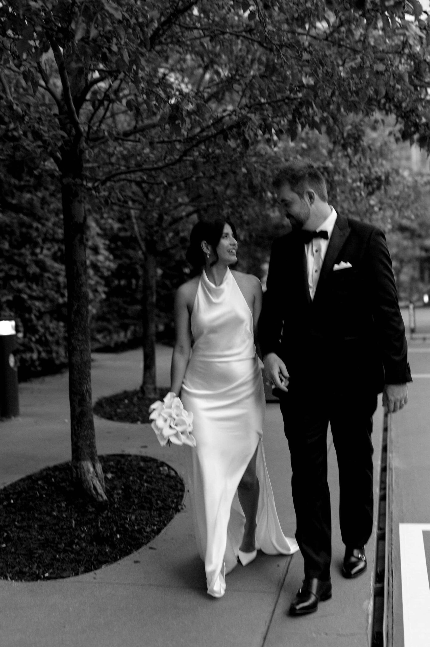 Bride and groom walking hand in hand outside 1 Hotel Toronto in a candid black and white moment.