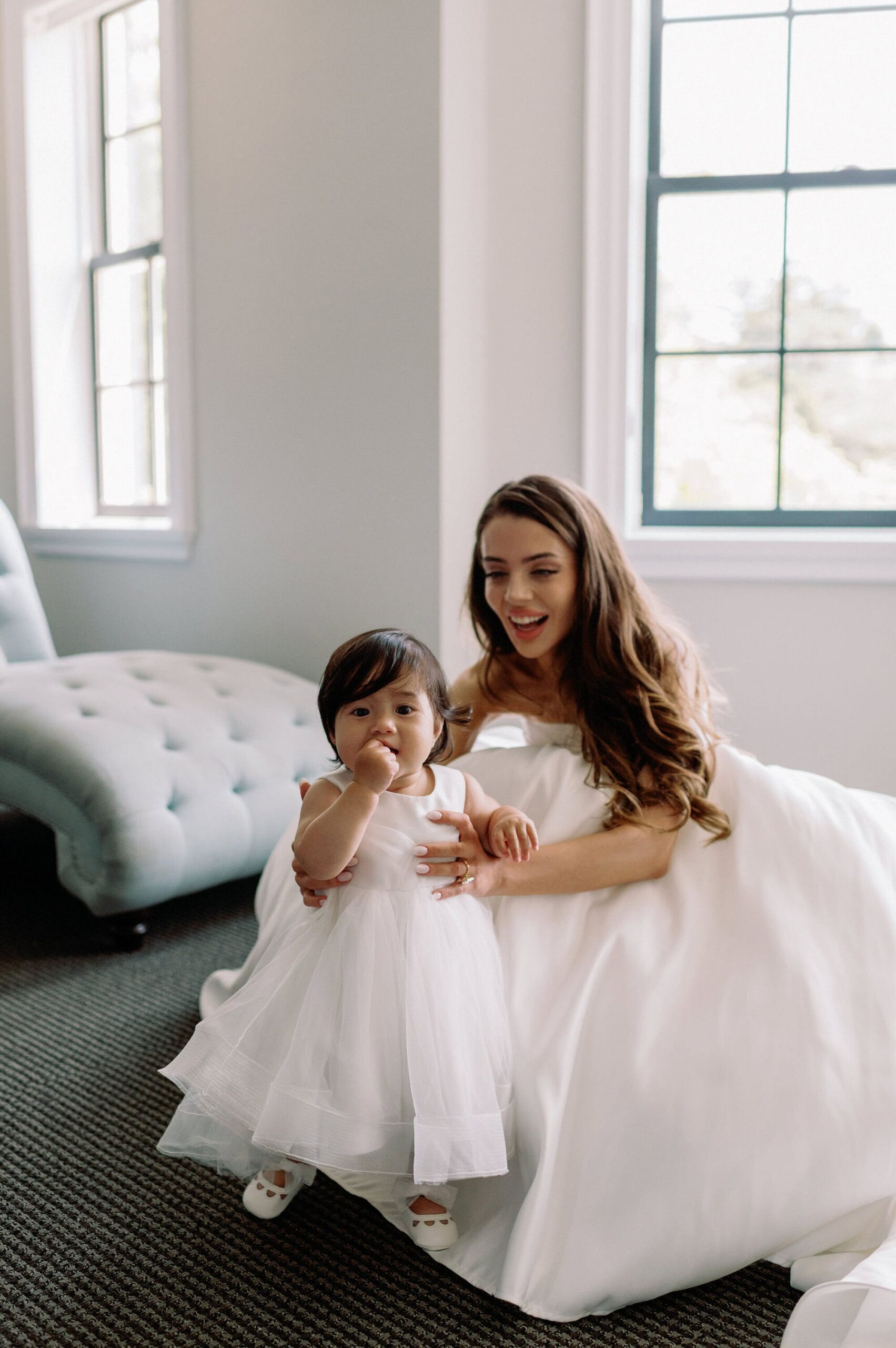 Bride sitting with the flower girl on her lap in the bridal suite at Harding Waterfront Estate.