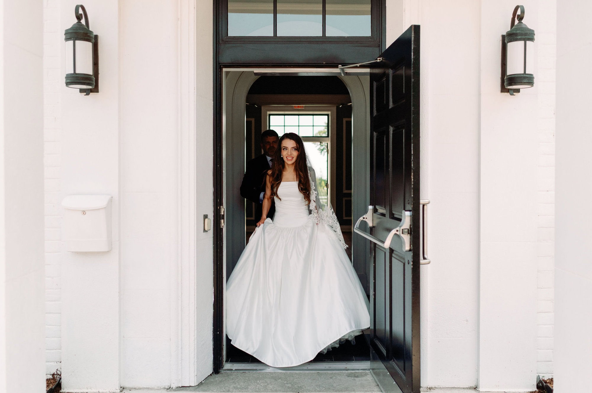 Bride entering the front doors of Harding Waterfront Estate for her wedding celebration.