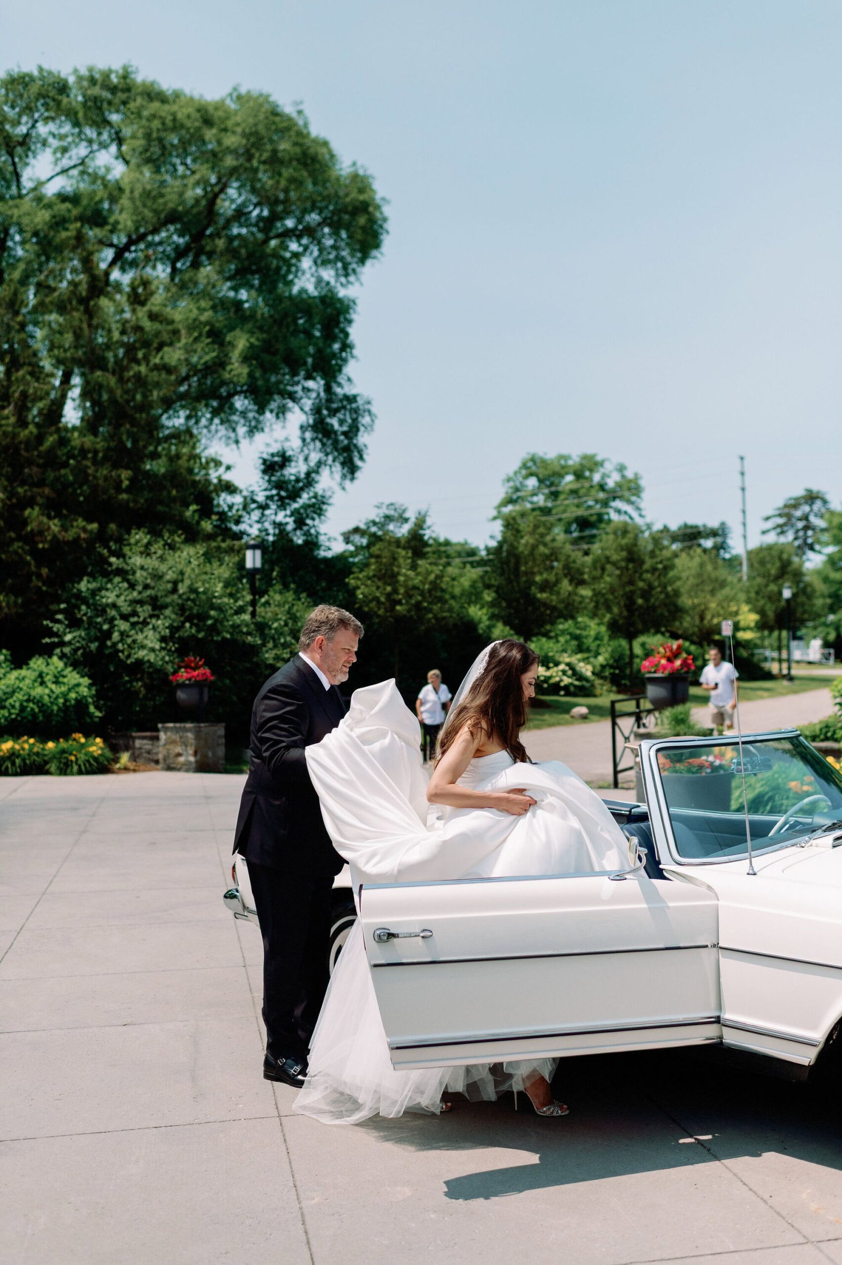Bride getting into a vintage white convertible for portraits at Harding Waterfront Estate.
