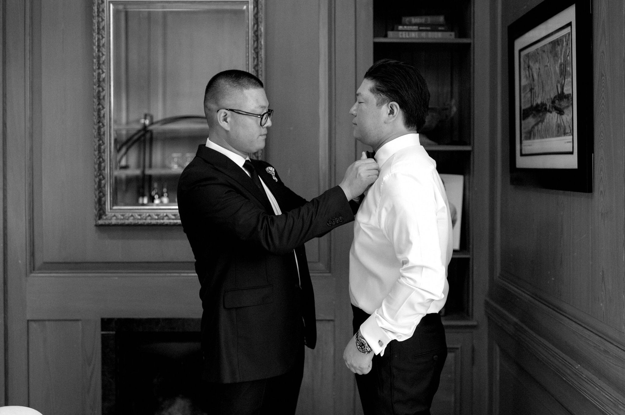 Groomsman adjusting the groom’s collar during getting ready moments at Harding Waterfront Estate