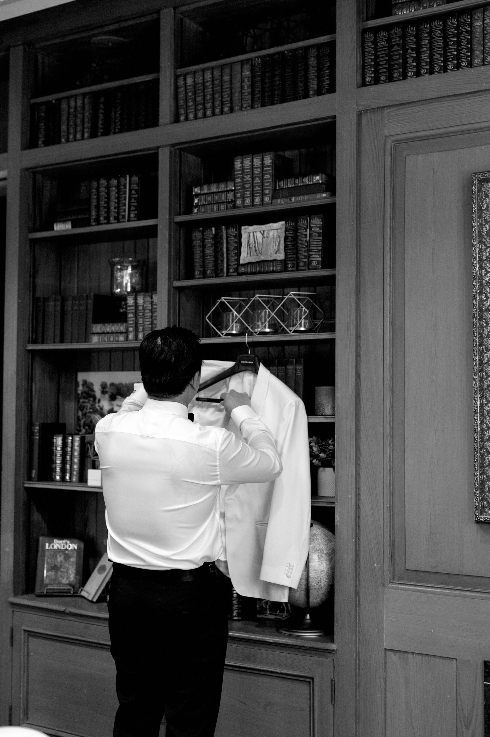 Groom adjusting his white tuxedo jacket during getting ready moments at Harding Waterfront Estate.