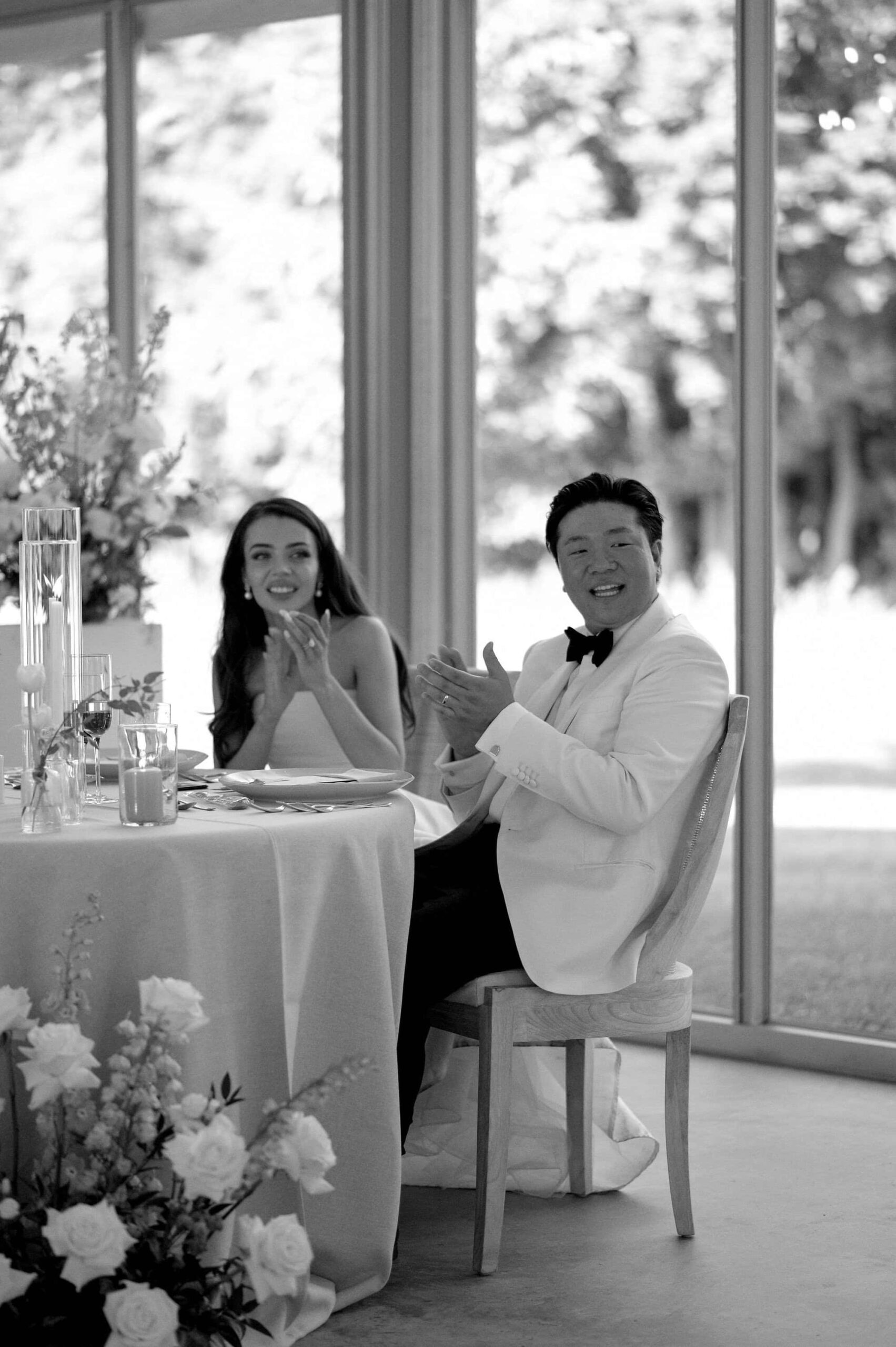 Black and white photo of the bride and groom seated at their sweetheart table at Harding Waterfront Estate.