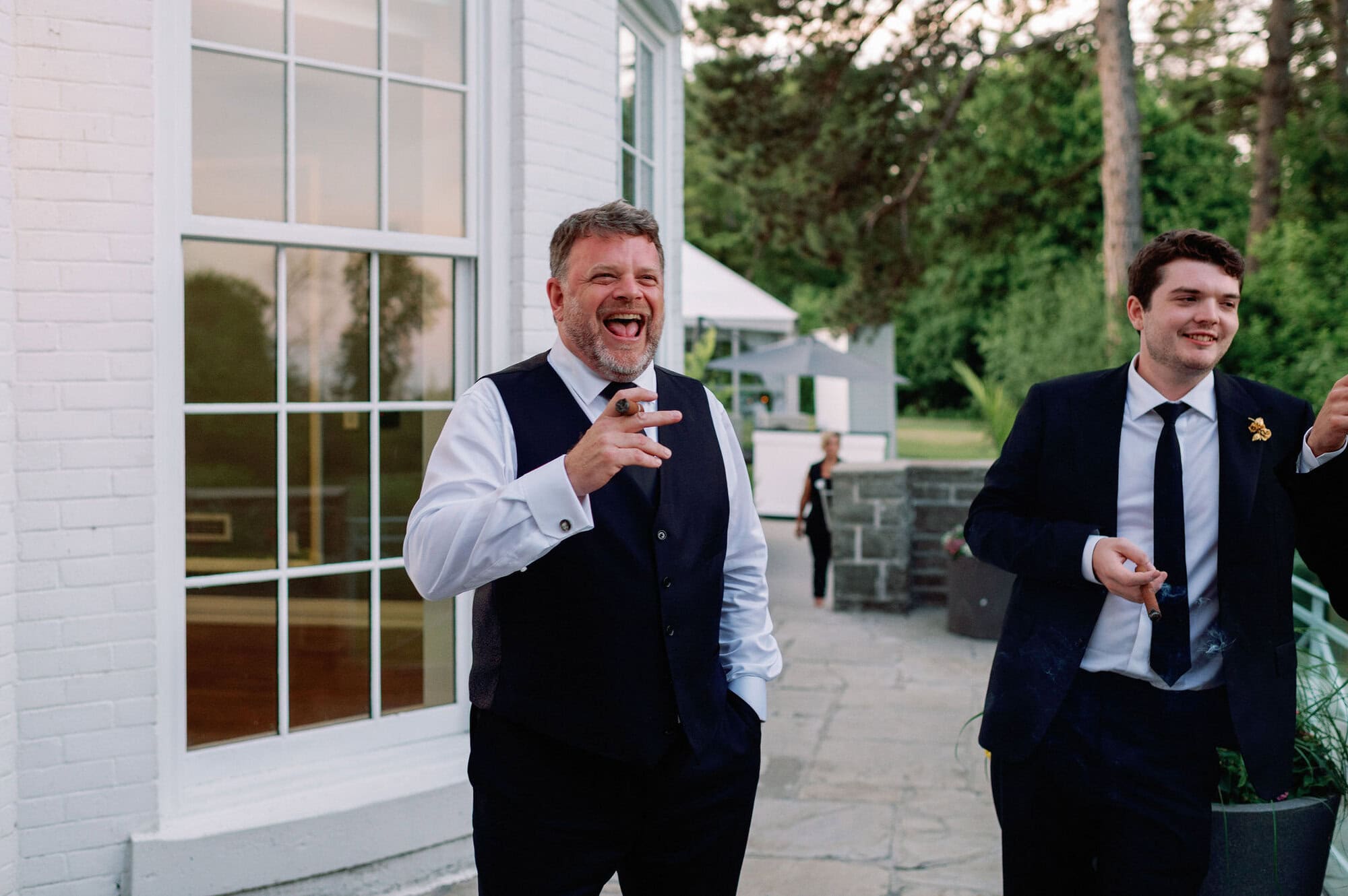 Wedding guests standing outside Harding Waterfront Estate enjoying cigars together