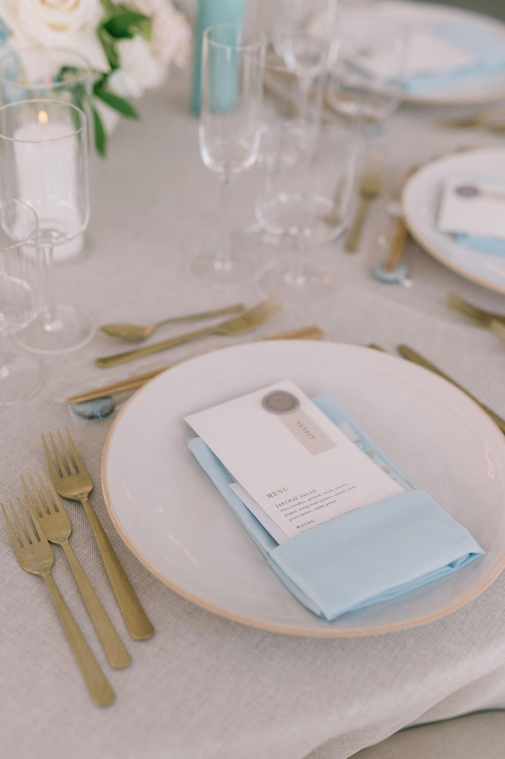 Elegant wedding place setting with a soft blue napkin and gold cutlery at Harding Waterfront Estate